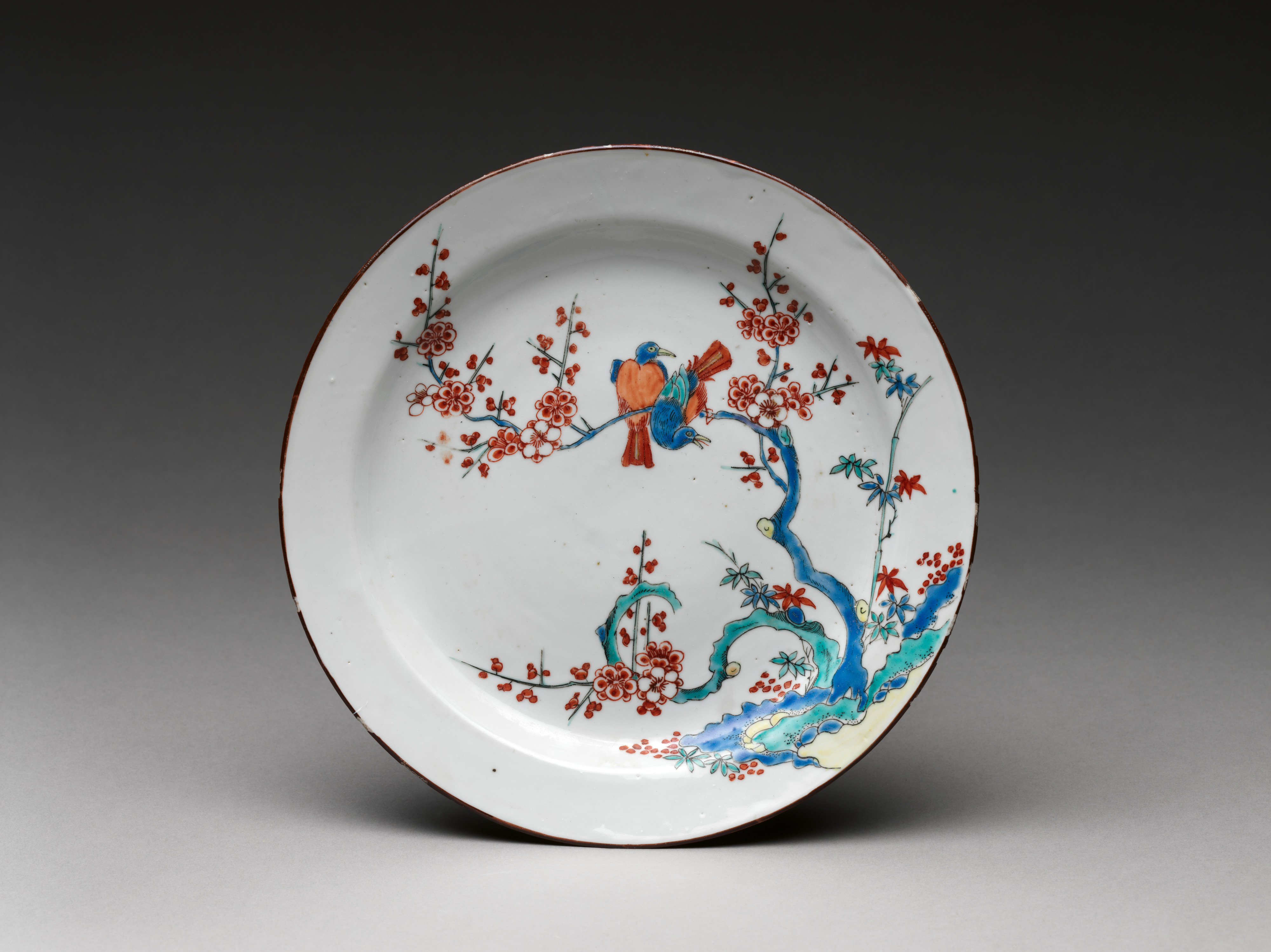 A white plate depicting an illustration of two birds sitting on the branch of a tree